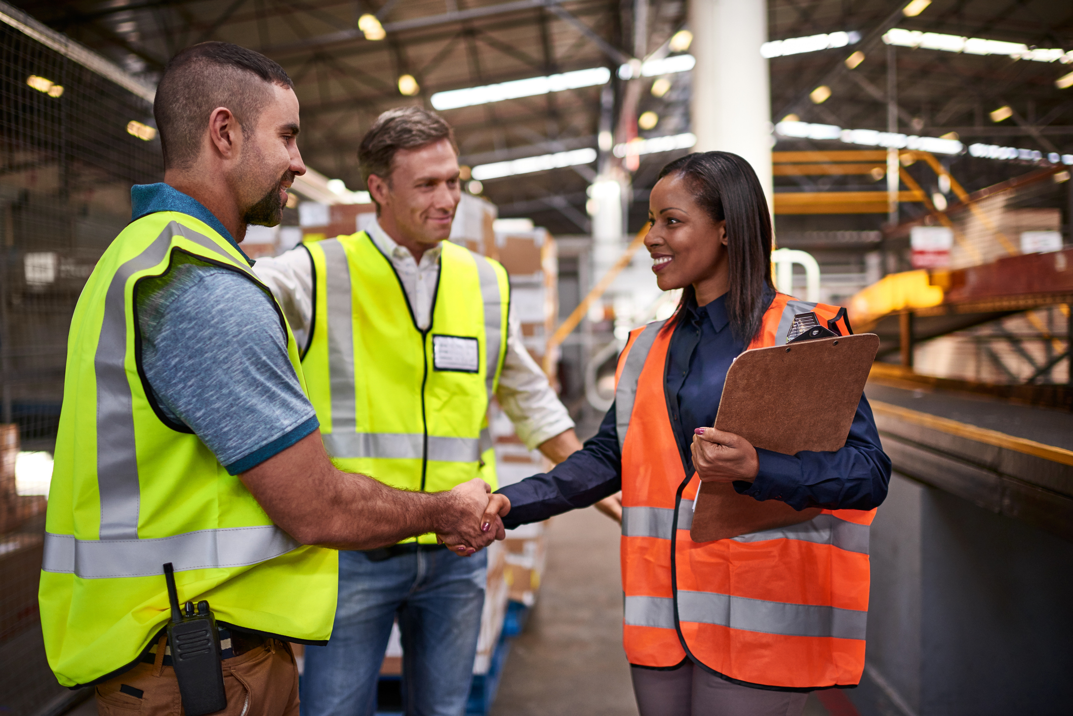 Shot of two workers shaking hands together while standing in a large warehouse